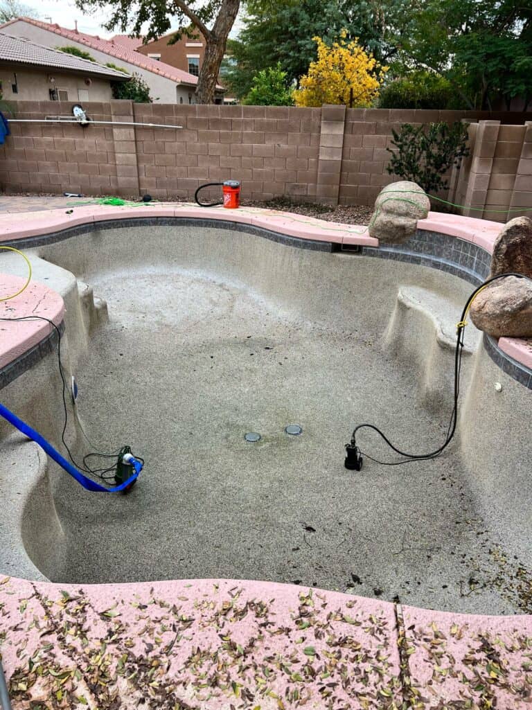 A pool being cleaned with a hose and a vacuum.